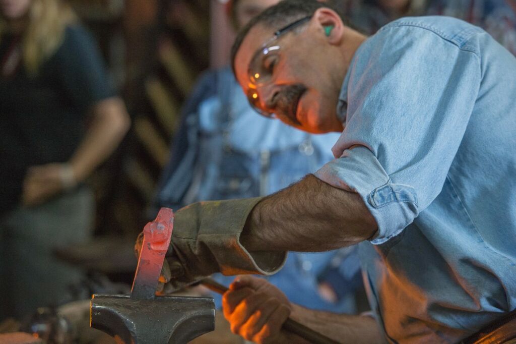 Image of Mark Aspery teaching a blacksmithing class. He is forging a bear head.