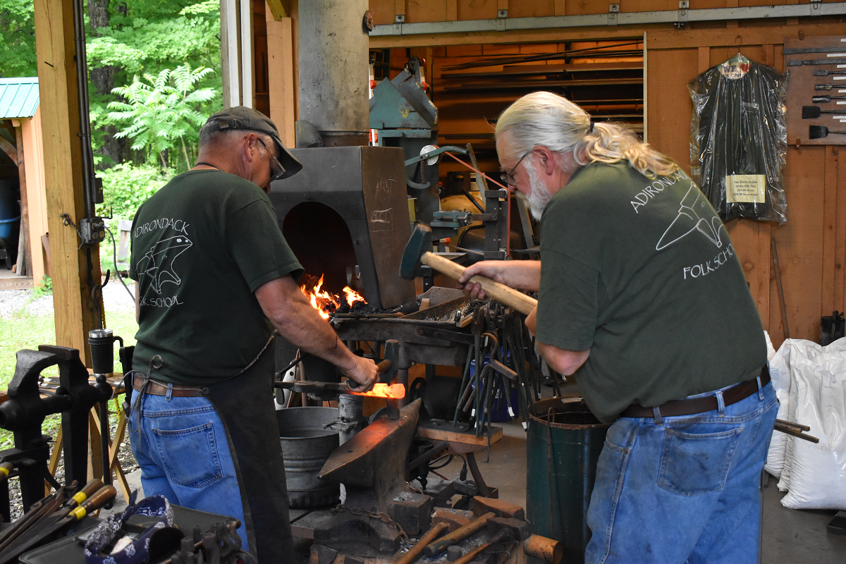 2 individuals giving a forging demonstrating at a blacksmith class at the Adirondack Folk School.