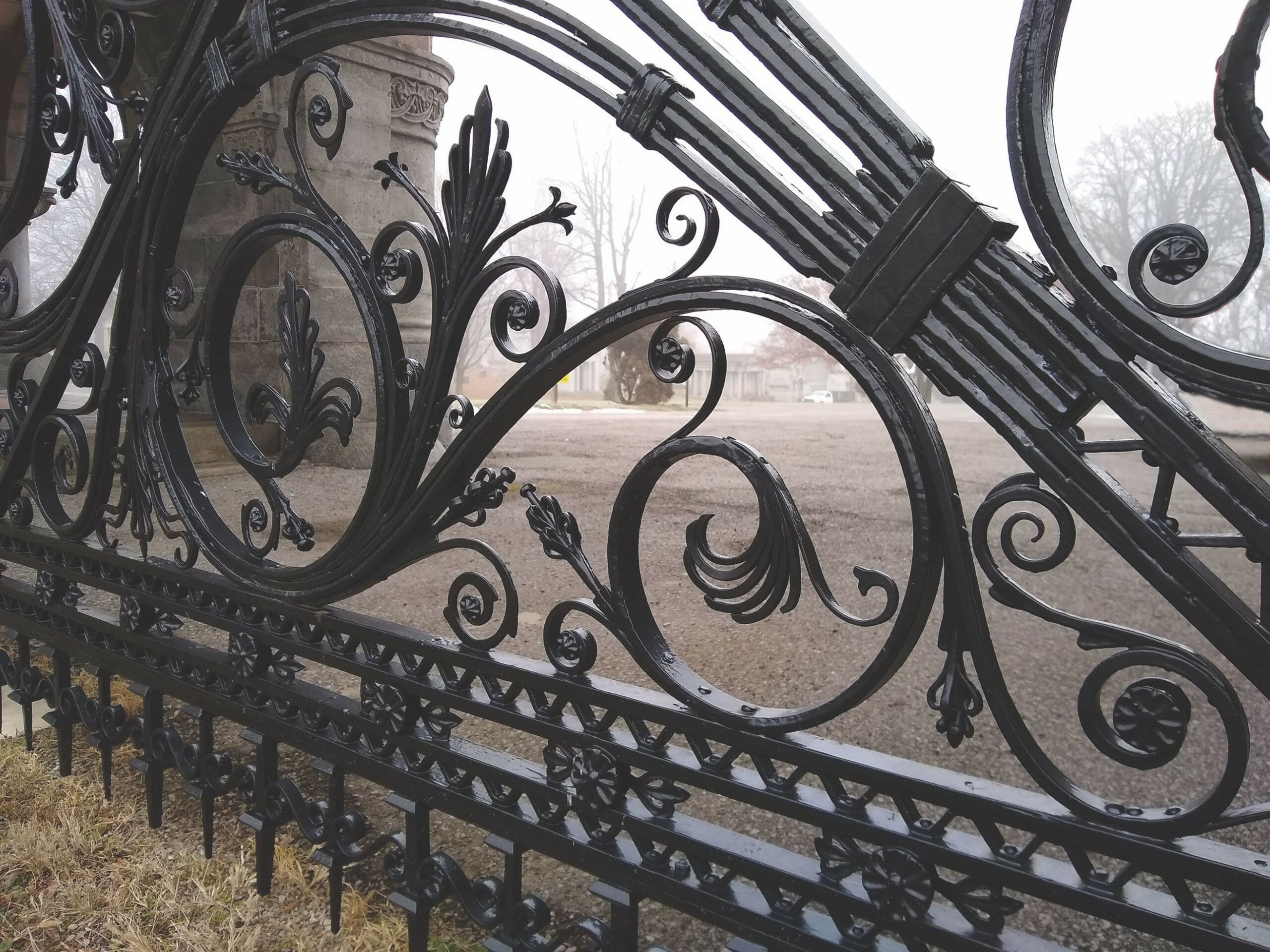 Close up picture of a fence with forged scrollwork and organic elements.